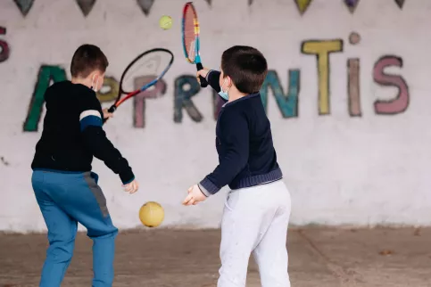 Deux élèves jouent au tennis dans une cour d'école.