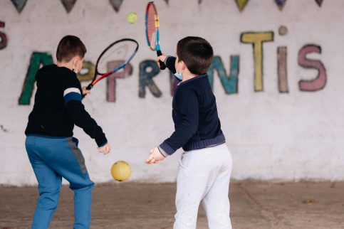 Deux élèves jouent au tennis dans une cour d'école.