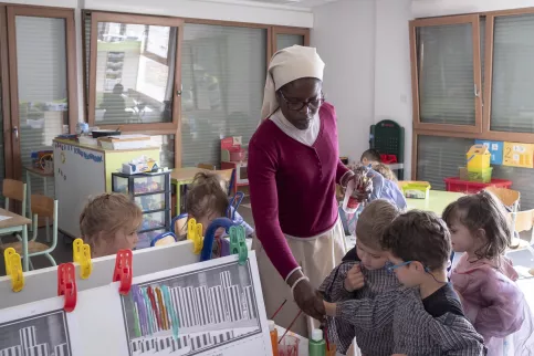 Soeur Cyprienne s'occupe d'enfants de maternelle qui font du dessin.