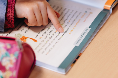 Un élève s'entraine à la lecture en suivant le texte du bout de son doigt.