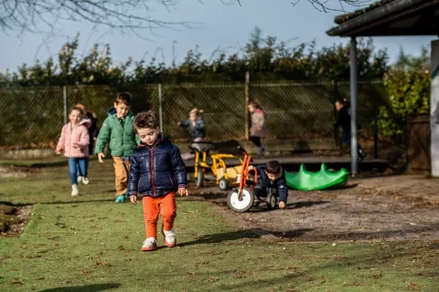 Des enfants de maternelle  jouent dans une cours d'école