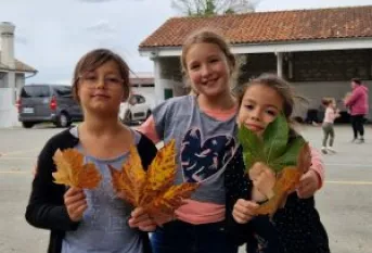 3 petites filles avec des feuilles d'automne dans les mains