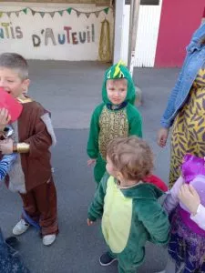 Petit garçon déguisé en dinosaure vert.