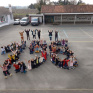 des élèves sont dans une cours d'école. Ils sont assis de façon à former le nombre 156.