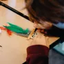 Un élève de maternelle crée un personnage en batonnets de bois pendant un cours d'art plastique.