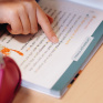 Un élève s'entraine à la lecture en suivant le texte du bout de son doigt.